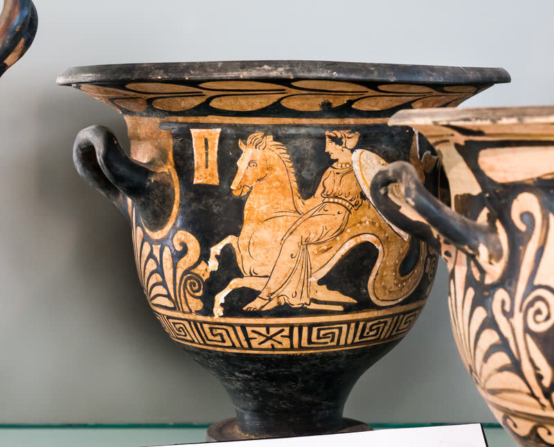 Uma nereida cavalga um hipocampo — cabeça e patas dianteiras de cavalo, corpo que termina em cauda de peixe — levando no colo um escudo, as armas que ela leva a Aquiles. Cratera de sino campaniense de figuras vermelhas, ca. 350–320 a.C., atribuída ao Pintor da Libação; achada na tumba 289 de Montesarchio, a antiga Cáudio. Museo del Sannio, Benevento.