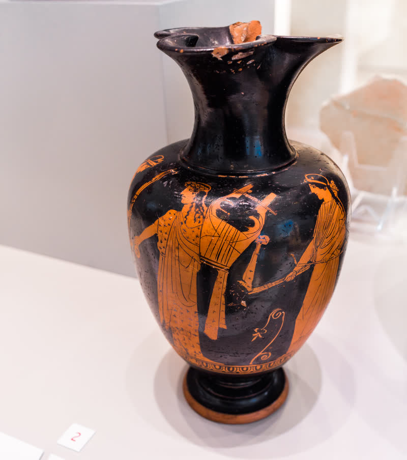 Leto de tocha na mão, Apolo com a cítara e Ártemis com o arco e a aljava. Oinócoe ático de figuras vermelhas, ca. 450–420 a.C., do Pintor de Munique 2528; achado em Vulci. Altes Museum · Antikensammlung, Berlim (F 2407).