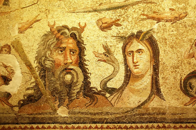 Oceano emerge da água, barbado e com as pinças de caranguejo erguidas na testa, e ao lado dele Tétis, de cabelo escuro caído sobre os ombros, com uma serpente marinha entre os dois; acima, peixes e camarões nadam sobre o fundo claro. Mosaico romano de Zeugma, Museu do Mosaico de Zeugma, Gaziantep.