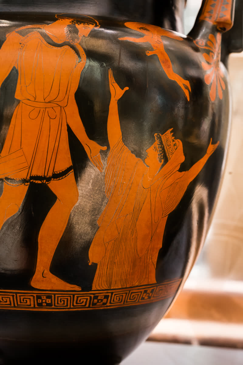 De perto: Epimeteu, com o malho na mão, e Pandora subindo da terra, coroada, com os dois braços abertos; Eros voa entre os dois. Detalhe do lado A da mesma cratera de volutas ática de figuras vermelhas, ca. 450 a.C. Ashmolean Museum, Oxford (V 525 / G 275).