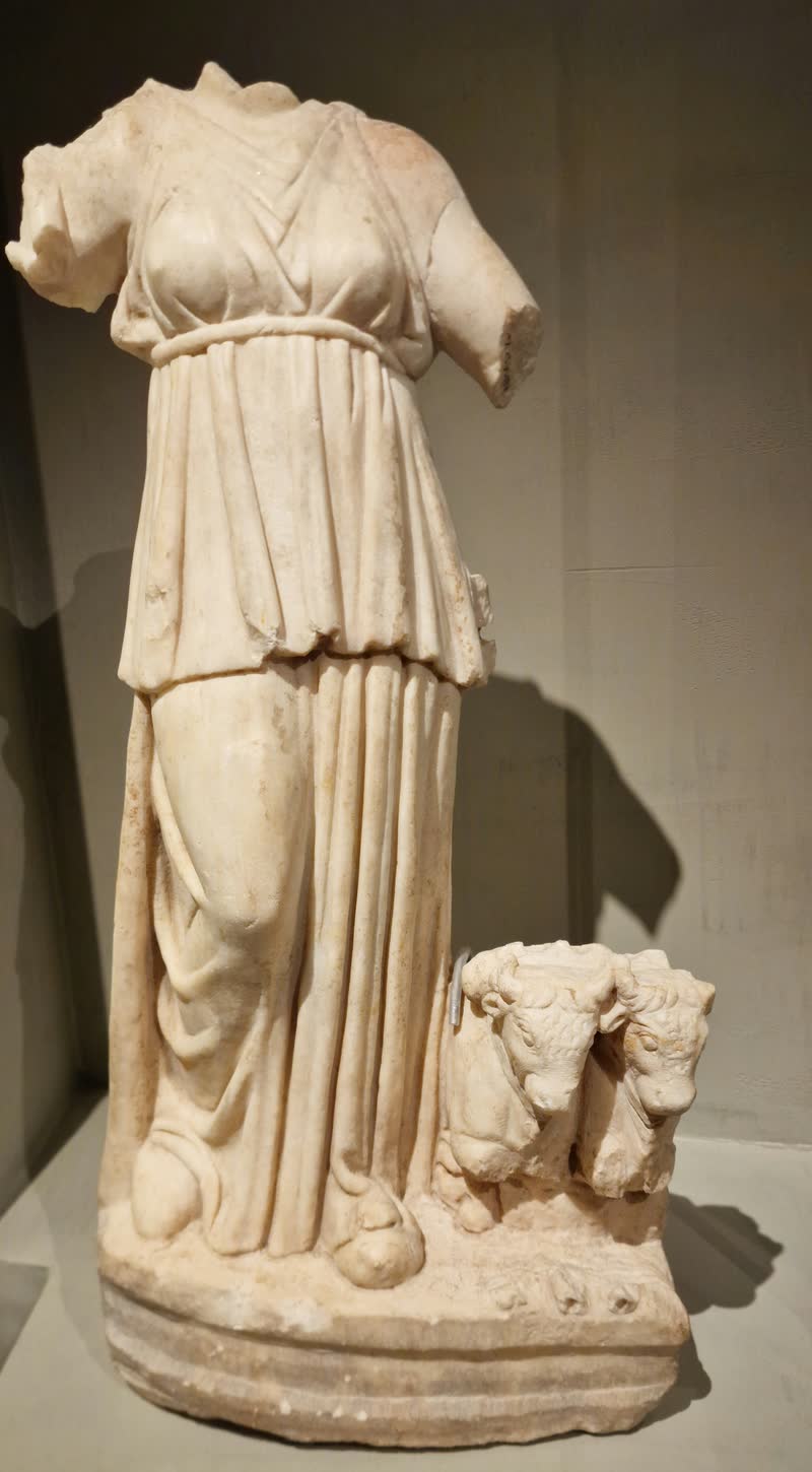 Selene caminha conduzindo a junta de bois que puxa seu carro — a cabeça e os braços se perderam. Estatueta de mármore de época romana, séculos I–II d.C. Museu da Acrópole, Atenas (NMA 127).