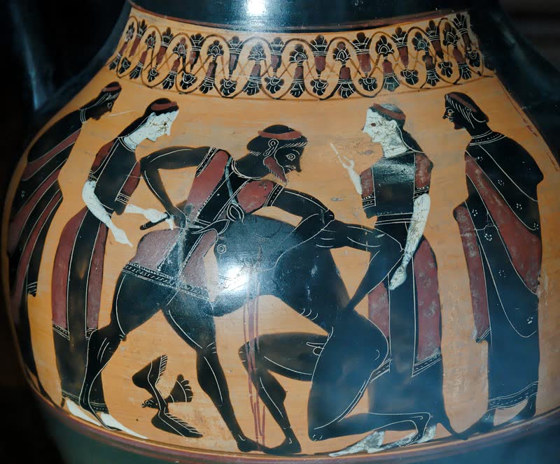 Teseu agarra o Minotauro pela cabeça e o força de joelhos, a espada na outra mão, entre quatro figuras de manto que assistem. Face A de uma ânfora ática de figuras negras, ca. 540 a.C., atribuída ao Grupo de Londres B 174. Museu do Louvre, Paris (F 33).
