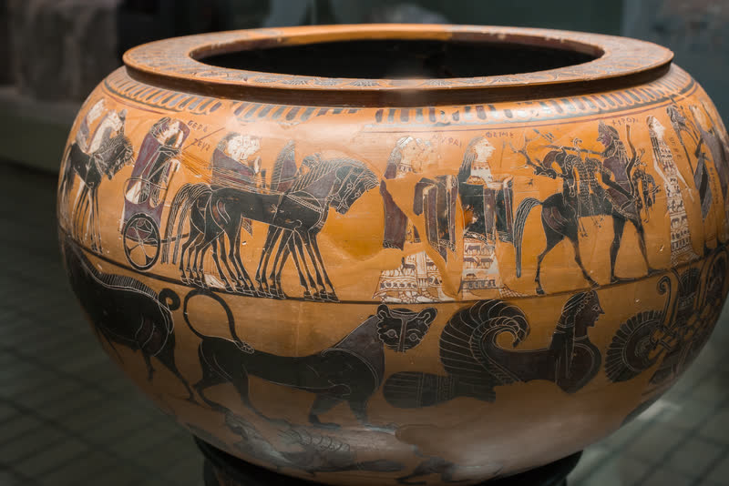 Os deuses chegam ao palácio de Peleu para as bodas com Tétis, cada um com o nome pintado ao lado: à esquerda Zeus na biga, ao centro as ninfas (ΝΥΜΦΑΙ) e Têmis (ΘΕΜΙΣ), e adiante Quíron (ΧΙΡΟΝ); embaixo, os frisos de animais. Dinos ático de figuras negras, ca. 580–570 a.C., assinado por Sófilos. British Museum, Londres (1971,1101.1).